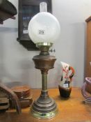 A brass oil lamp with shade and chimney