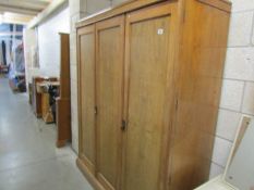 A pale mahogany triple door wardrobe