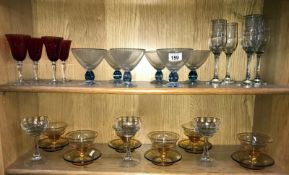 2 shelves of coloured & clear drinking glasses