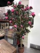 An artificial tree with pink flowers in pot