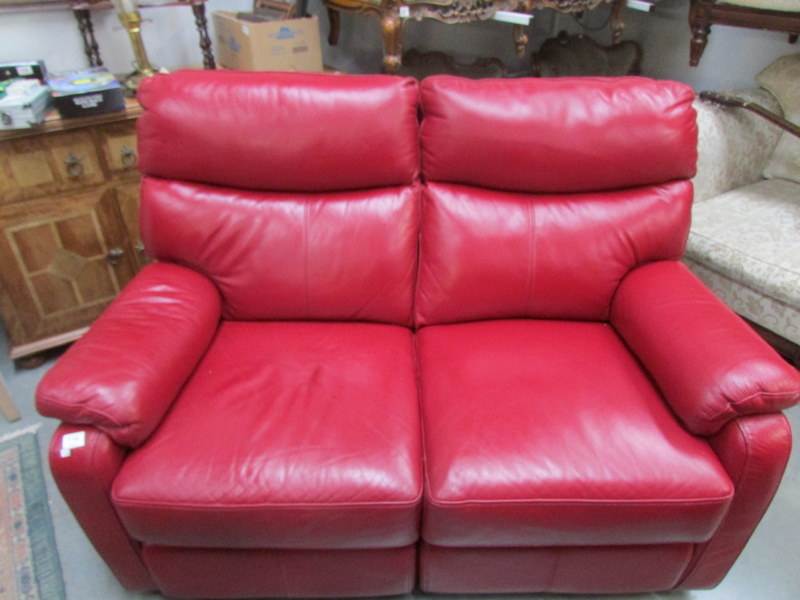 A 2 seat burgundy leather reclining sofa.