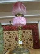 A Victorian brass oil lamp with cranberry glass shade