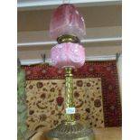 A Victorian brass oil lamp with cranberry glass shade