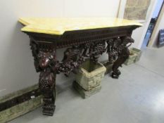 A carved mahogany console table with marble effect top.