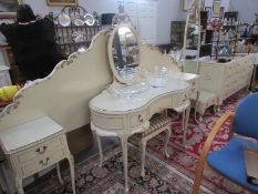 A French style headboard with attached bedsides, a matching cheval mirror, dressing table,