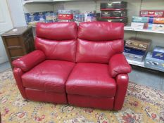 A 2 seat burgundy leather reclining sofa.