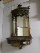 An ornate oak wall mirror with shelf and drawer.