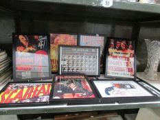 A shelf of framed and glazed entertainment advertisements.