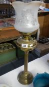 A brass oil lamp with shade and chimney.