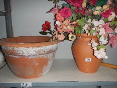 A large terracotta pot and a terracotta vase with silk flowers,.