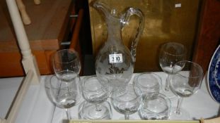 An etched glass jug and a quantity of wine glasses.