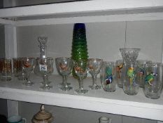 A shelf of glass ware including decorated glasses.