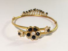 A yellow metal bracelet featuring floral crossover design set with cubic zirconia,