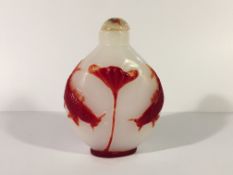 A circa 19/20th century red overlay carved glass snuff bottle depicting 2 carp under a lily pad and