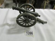 A brass model of a cannon painted green.