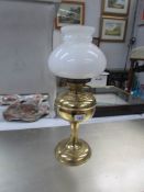 A brass oil lamp with shade and chimney.