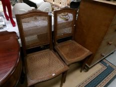 A pair of chairs with cane seats and backs.