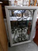 A framed mirror with wrought iron panel inset.