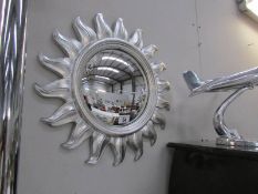 A silver coloured sunburst mirror.