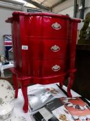 A red coloured 3 drawer chest.