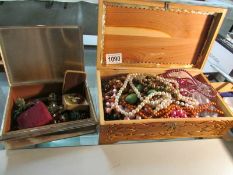 A wooden box containing necklaces and metal box containing earrings.