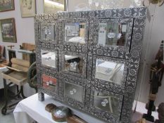 A silver coloured 9 drawer chest with mirrored top and mirrored drawer fronts.