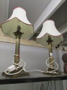 A pair of brass Corinthian column table lamps with shades.