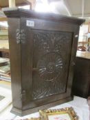 An oak corner cupboard with carved door,