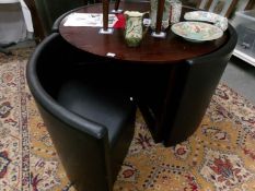A modern circular dining table with 4 black nesting chairs,