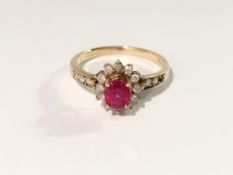 A ruby and diamond oval cluster ring within a surround of circular cut diamonds in 9ct gold,