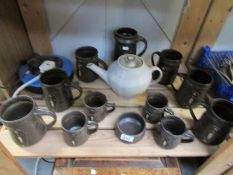 A shelf of studio pottery tankards, jug,