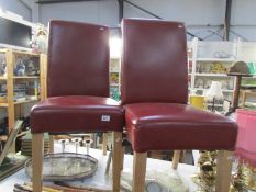 A pair of red faux leather dining chairs