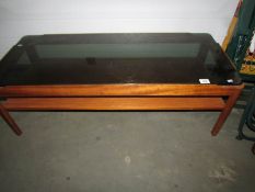 A teak coffee table with smoked glass top.