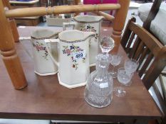 A set of 3 graduated jugs, liquor decanter and glasses.