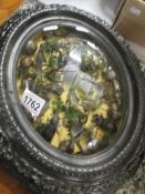 A collage of insects etc in ornate domed frame.