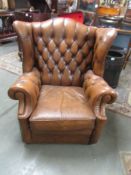 A tan leather wing armchair.