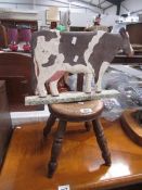 An old milking stool and a wooden cow model,.