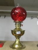 A brass oil lamp with ruby glass shade.