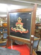 An oak fire screen embroidered with military badge.