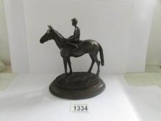 A bronze figure of a race horse and jockey.