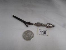 A 1902 silver dollar and a pair of silver handled glove stretchers.