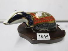 A Royal Crown Derby paperweight, Badger on wooden stand.