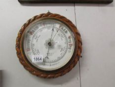 An Edwardian oak barometer with pie crust edge and porcelain face by Symons & Son, Lancaster.