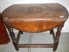 An oak gate leg table with carved top.