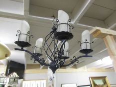 A wrought Iron 5 lamp ceiling light with frosted glass shades.