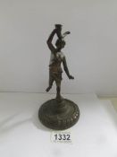 An antique bronze figure of a young woman with a horn on a circular base.