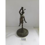 An antique bronze figure of a young woman with a horn on a circular base.
