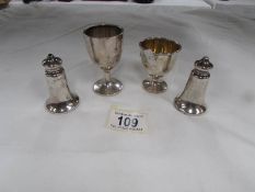 2 silver egg cups together with silver salt and pepper pots.