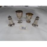 2 silver egg cups together with silver salt and pepper pots.