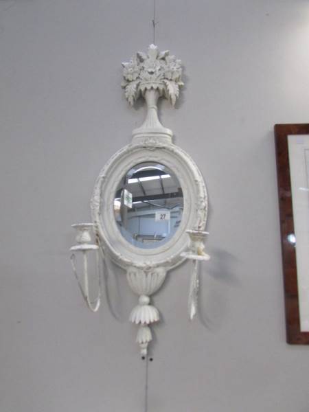 A shabby chic wall mirror with candle sconces.